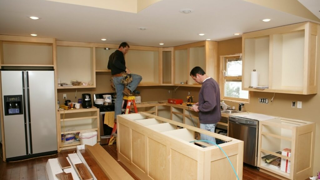 Two workers in the kitchen in the middle of a luxury remodeling project.